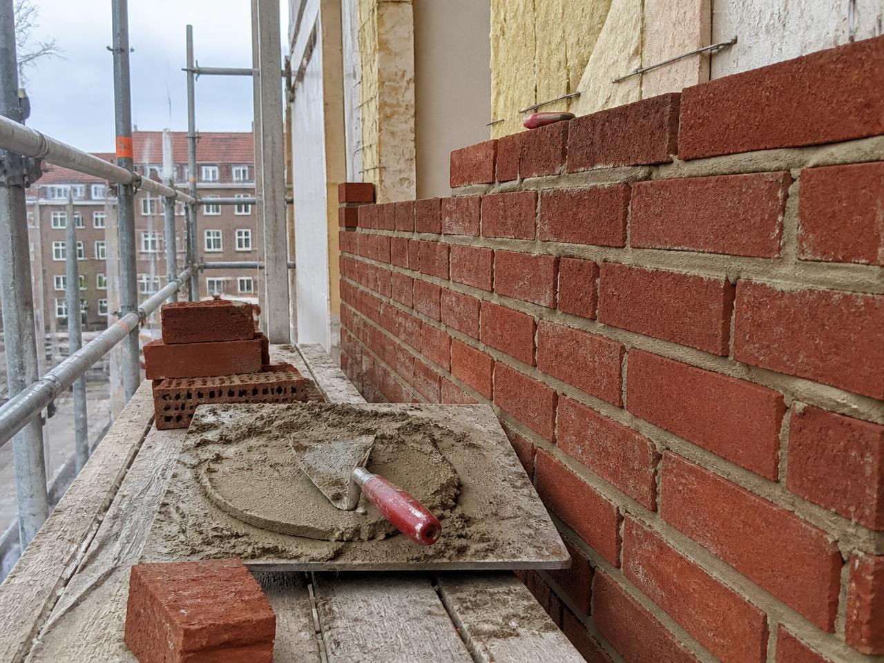 Murer arbejder på en muret facade under renovering af en ældre ejendom